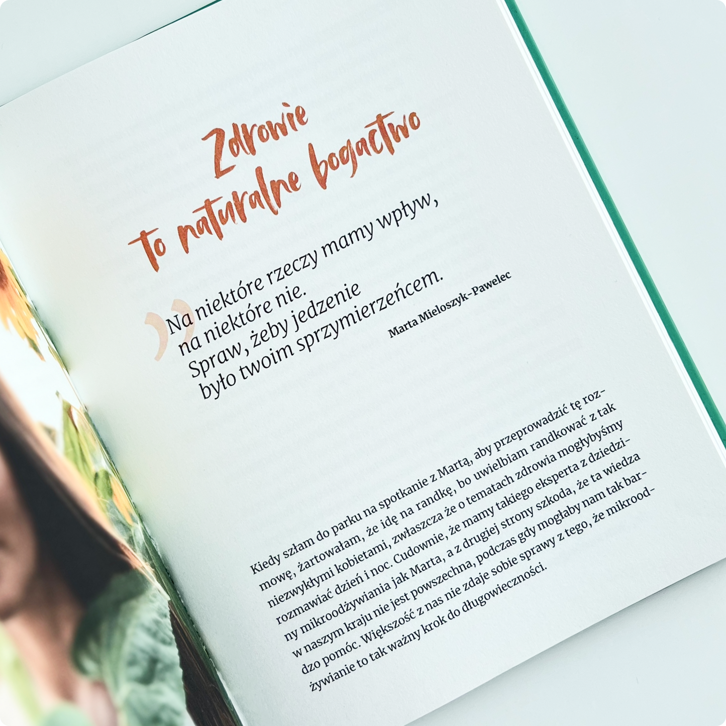 Strona książki z cytatem Marty Mieloszyk-Pawelec: „Zdrowie to naturalne bogactwo. Na niektóre rzeczy mamy wpływ, na niektóre nie. Spraw, żeby jedzenie było twoim sprzymierzeńcem.” – na tle jasnych stron publikacji o zdrowiu i odżywianiu.