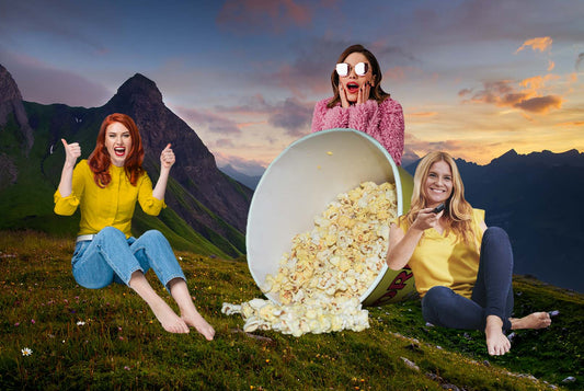 Uśmiechnięte kobiety jedzą popcorn i wybierają film o gotowaniu na piątkowy wieczór