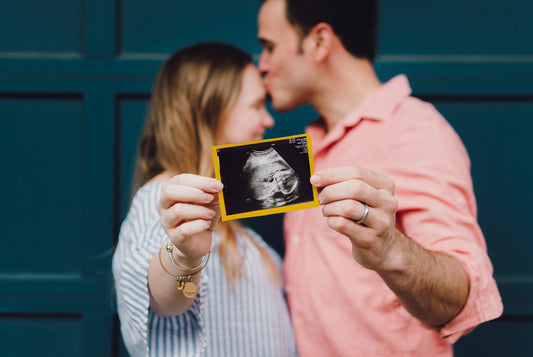 Szczęśliwa para ze zdjęciem z USG ciążowego, która skorzystała z porad na temat tego, co pomaga zajść w ciążę.