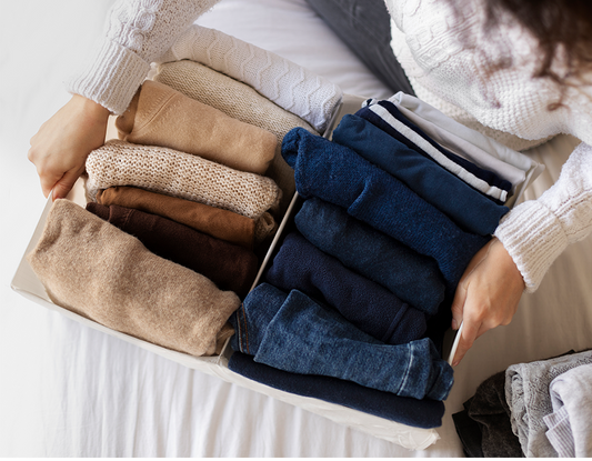 Kobieta w środku sterty z odzieżą zastanawia się, co zrobić ze starymi ubraniami.