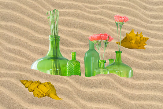 Szklane butelki w piasku, który jest wydobywany na skalę masową, żeby wytworzyć szkło.