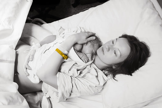 Kobieta z noworodkiem na rękach, która doświadczyła przemocy podczas porodu.