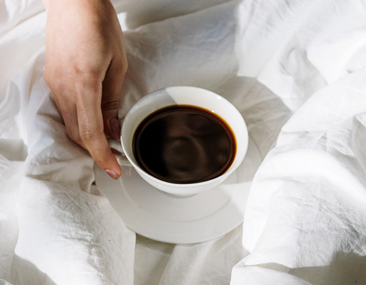 Biała filiżanka ze spodkiem, wypełniona kawą. Pytanie: kawa wypłukuje magnez fakt czy mit? Logo nikalab.