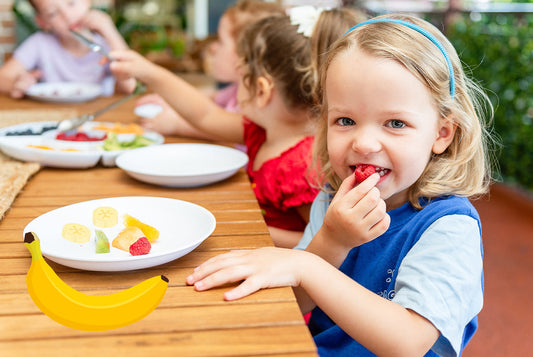 Dziewczynka w przedszkolu je owoce podczas obiadu