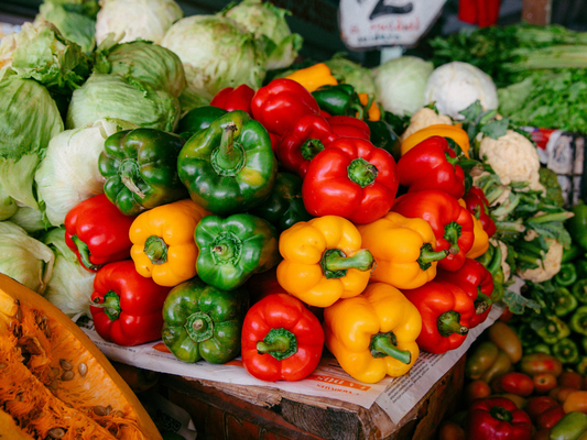 Kolorowe papryki i świeże warzywa na targu – inspiracja do jedzenia różnorodnych, zdrowych posiłków.