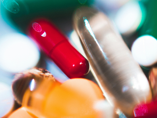 Kolorowe kapsułki i tabletki symbolizujące różnice między lekiem a suplementem diety.