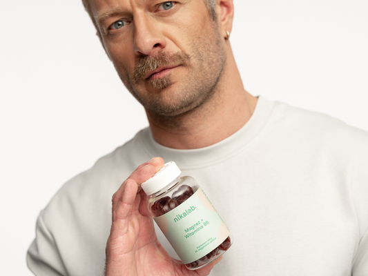 Mężczyzna trzyma suplement diety nikalab Magnez + Witamina B6 w żelkach, wspierający mięśnie, regenerację i energię.