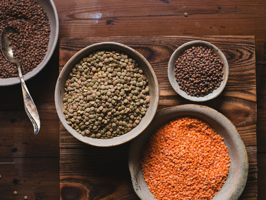 Miski z soczewicą zieloną, czerwoną i innymi roślinami strączkowymi na drewnianym stole jako źródła błonnika pokarmowego.