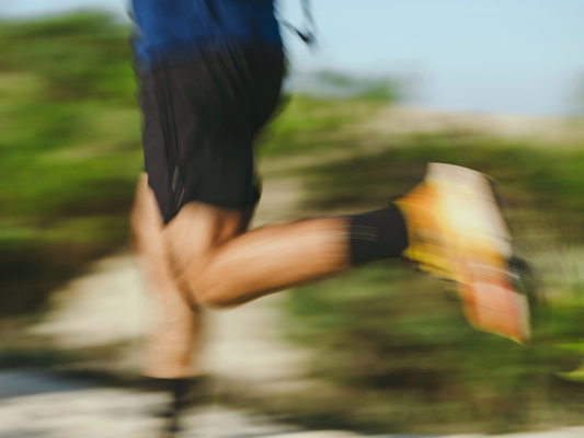 Rozmyte, dynamiczne ujęcie nóg osoby biegnącej na zewnątrz.