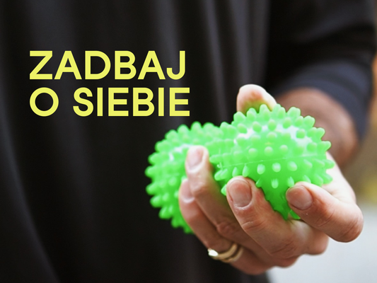 Dłoń ściskająca dwie zielone, kolczaste piłki do masażu na czarnym tle z napisem „Zadbaj o siebie”, nawiązująca do profilaktyki i samobadania jąder.