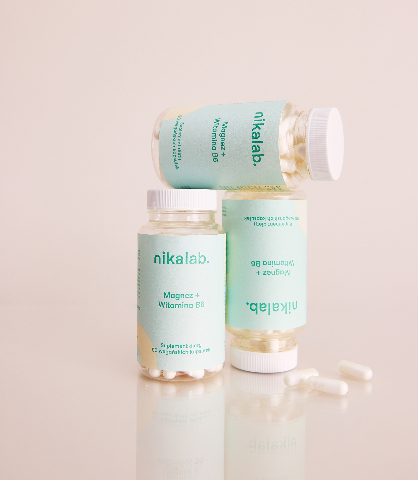 Trzy butelki suplementu diety Magnez + Witamina B6 marki nikalab, ustawione jedna na drugiej, na jasnym tle; obok widoczne kapsułki.