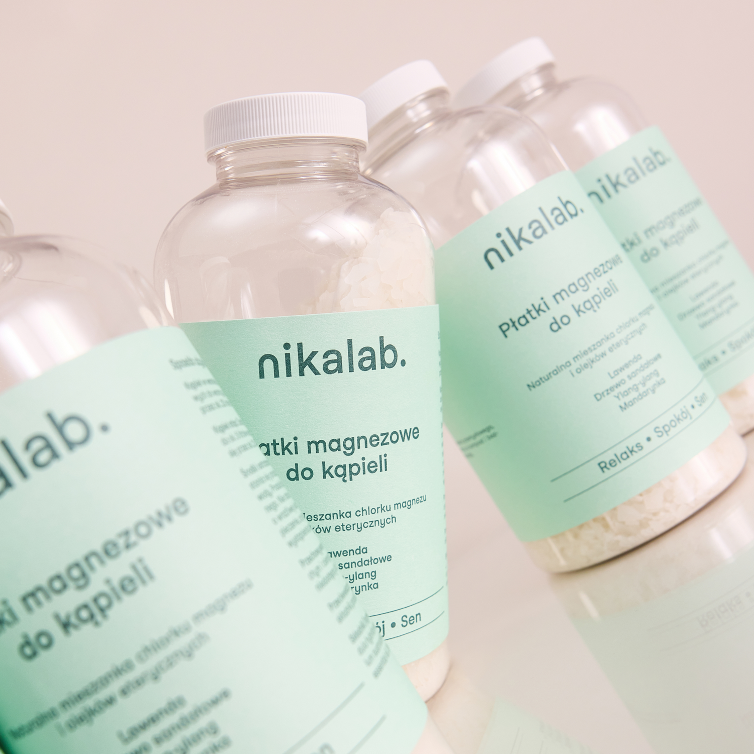 Butelki płatków magnezowych do kąpieli marki nikalab z jasnozieloną etykietą, przeznaczone do relaksu i poprawy jakości snu, ustawione na jasnym tle.