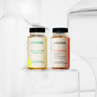 Zestaw dwóch suplementów diety nikalab: Baza na co dzień dla kobiet 18–49 lat (60 wegańskich kapsułek) i Formuła Blasku (60 wegańskich kapsułek) – oba w biodegradowalnych słoiczkach z jasnymi etykietami.