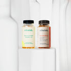 Zestaw dwóch suplementów diety nikalab: Baza na co dzień dla kobiet 50+ lat (60 wegańskich kapsułek) i Formuła Blasku (60 wegańskich kapsułek) – oba w biodegradowalnych słoiczkach z jasnymi etykietami.